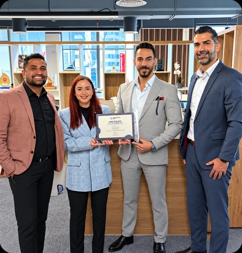 Four people at the Innovation City office, two holding a framed certificate